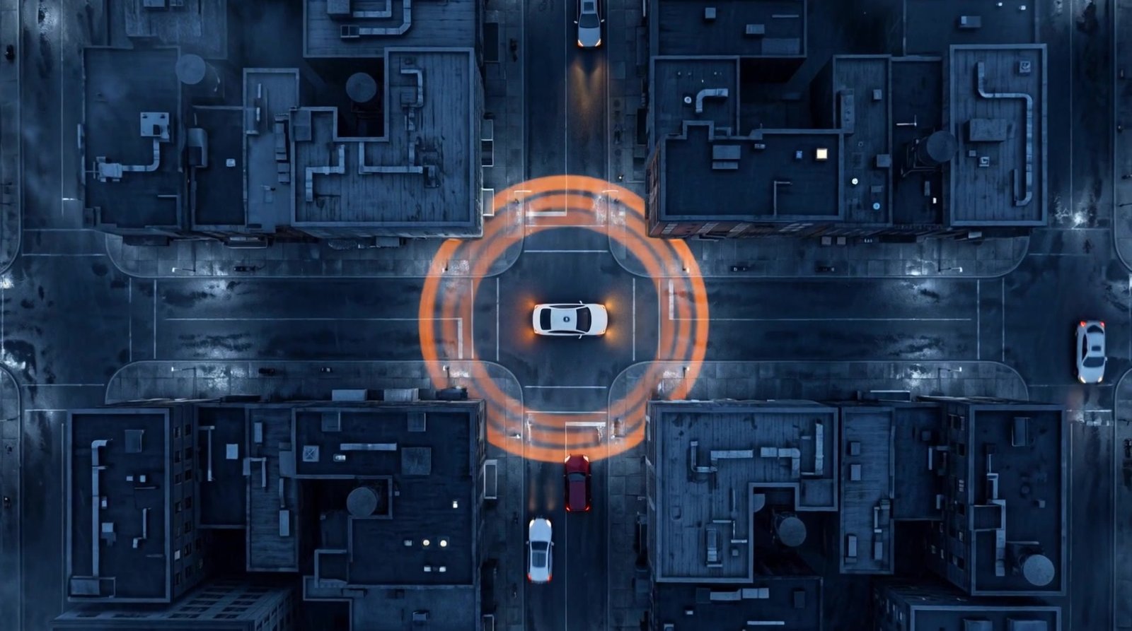 Seen from high above at night, a white driverless car stopped at a city intersection, circled by orange rings of light